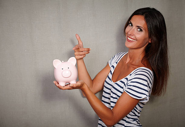 istock Happy youngster pointing a piggy bank 496025856