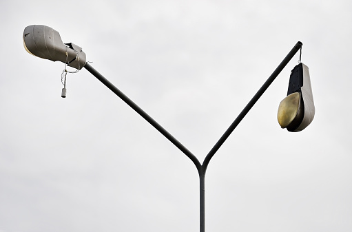 Detail shot with a broken street lamp with overcast sky on background