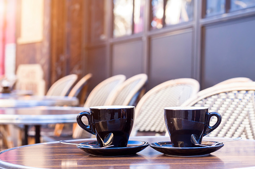 Two cups of coffee on restaurant terrace with afternoon sunlight