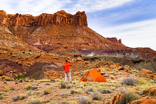 Camping in Remote Red Rock Canyon Camping in Remote Red Rock Canyon - Tent and man awaken at sunrise and enjoy the view while drinking hot coffee.  Utah, USA. escalante stock pictures, royalty-free photos & images