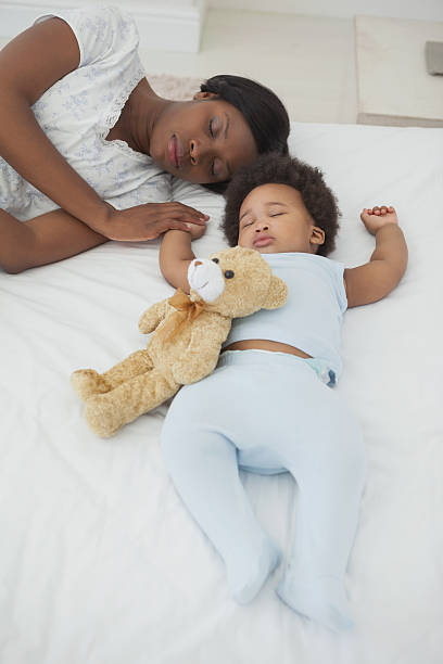 istock Cute Afro baby with mother sleeping in bed 496031751