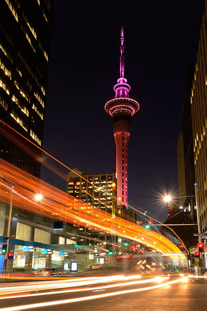 Motion traffic light trail of vehicles in Auckland CBD in the foreground with the Sky Tower in the background at dusk. Vertical