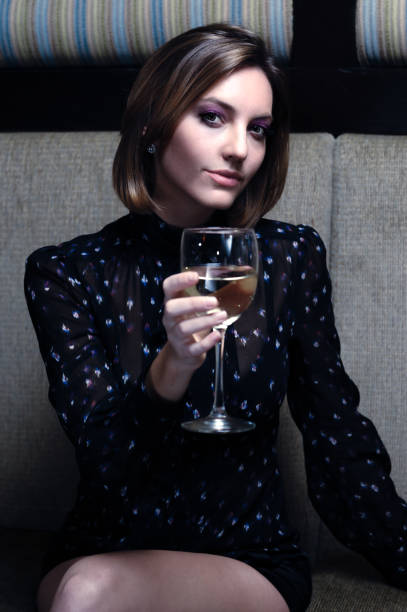 Twenty-something blonde woman drinking white wine alone in a bar