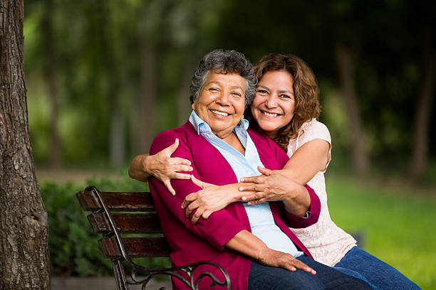 Senior mother sitting with daughter A senior mother sitting and posing for the camera in the park. hispanic grandmother stock pictures, royalty-free photos & images