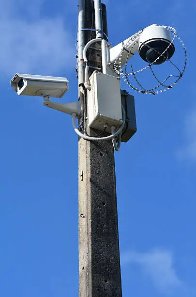 Two security surveillance cameras on a high pole at the park.concept photo of security.