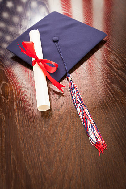 istock Graduation Cap and Diploma on Table with American Flag Reflectio 496034019