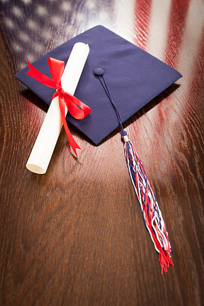 istock Graduation Cap and Diploma on Table with American Flag Reflectio 496034023