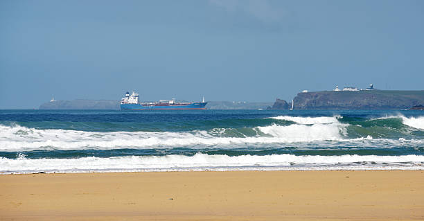 Oil Tanker entering Milford Haven Milford Haven, United Kingdom - May 13, 2015: Long distance view of the Danish-registered oil products tanker, Bro Designer, passing the lighthouse at Angle and entering Milford Haven, Wales, United Kingdom, on route to the oil terminal there. The ship entered service in 2006 and is a regular visitor to ports in the Bristol Channel and Eire such as Avonmouth, MIlford Haven and Dublin.The beach in the foreground is at Freshwater West, Pembrokeshire.. milford haven stock pictures, royalty-free photos & images