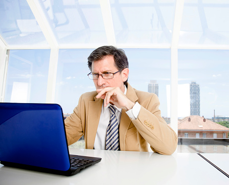 Mid aged businesman looking at his computer,facin problemes.