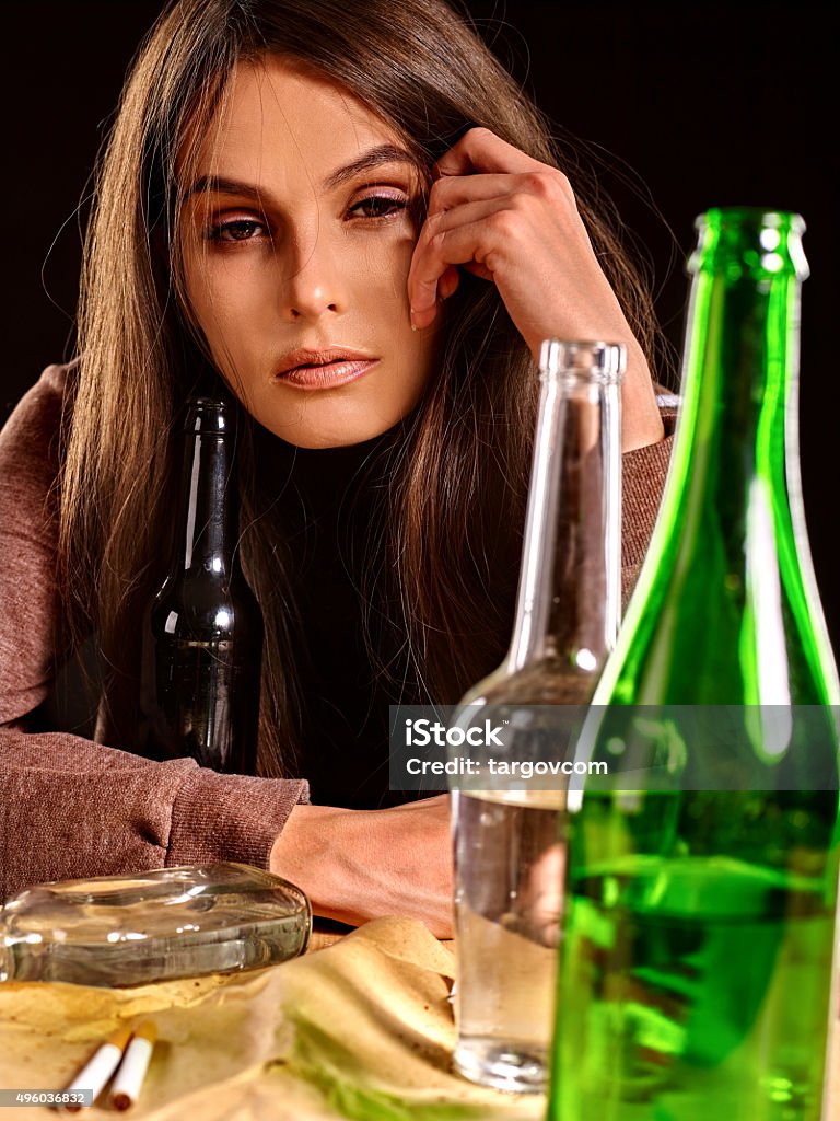 Drunk girl holding bottle of vodka Drunk girl sitting near bottle of alcohol. Soccial issue alcoholism. 2015 Stock Photo