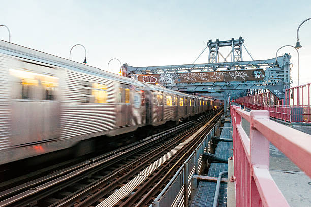 NYC Public Transportation Subway Train Crosses Williamsburg Bridge Into Brooklyn New York City, United States - October 22, 2015: An MTA subway train providing public transportation drives across the Williamsburg Bridge connecting Brooklyn to Manhattan. The transportation vehicle passes by in a motion blur. williamsburg bridge photos stock pictures, royalty-free photos & images