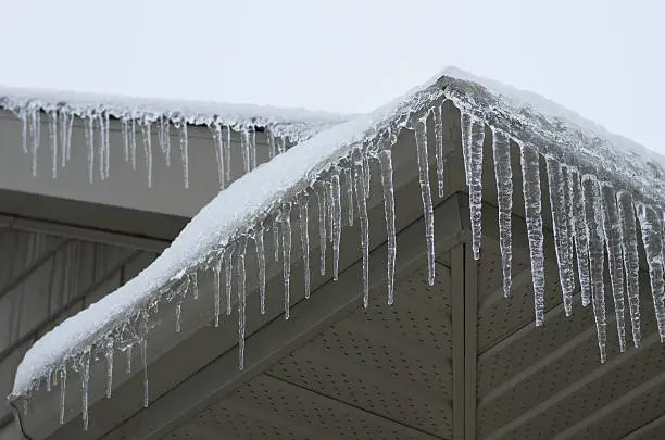 Icicles forming on the evestrough of a house after a winter ice storm.