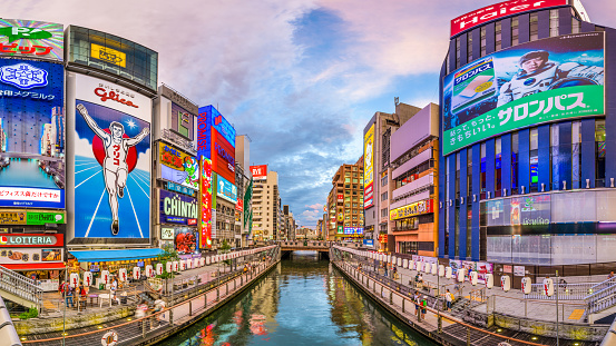 Osaka, Japan - August 16, 2015: Tourists walk along the Dotonbori Canal in the Namba District. The canal dates from the early 1600's and is now a popular commercial district and tourist attraction.