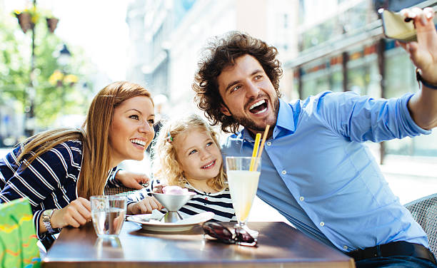 istock Cheerful Family Sitting In A Restaurant Outdoors And Making Selfie. 496038337