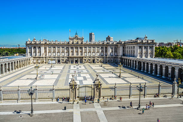 madrid royal palace – außenansicht - spain flag built structure cloud stock-fotos und bilder