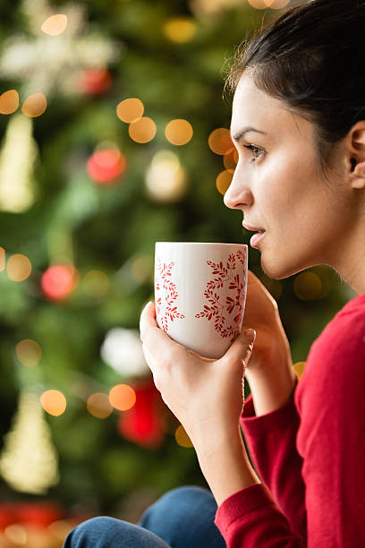 istock Woman drinking warm drink next to the Christmas tree 496069574