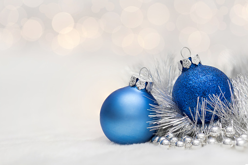 Blue Christmas balls with garland. Bokeh effect on white background. Copyspace for your greeting or wishes