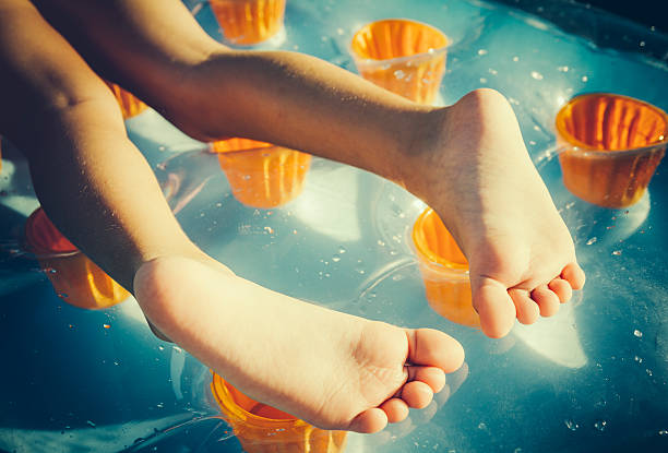Shoot Planner Ref #107 - Beach lifestyle moments - Young girl is lying down on the pool raft sunbathing. A closeup of her feet. Retro toned, AdobeRGB profile.