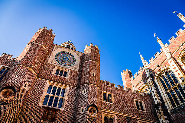 London, UK - 26 October, 2015: exterior image of Hampton Court Palace on a crisp autumn day. Hampton Court Palace is a royal palace in the London Borough of Richmond upon Thames, Greater London, in the historic county of Middlesex, and within the postal town East Molesey, Surrey. It has not been inhabited by the British Royal Family since the 18th century. The palace is 11.7 miles (18.8 kilometres) south west of Charing Cross and upstream of central London on the River Thames. Redevelopment began to be carried out in 1515 for Cardinal Thomas Wolsey, a favourite of King Henry VIII. In 1529, as Wolsey fell from favour, the King seized the palace for himself and later enlarged it. Along with St. James's Palace, it is one of only two surviving palaces out of the many owned by King Henry VIII. Horizontal colour image.