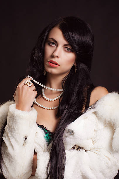 Beautiful girl with dark hair in a white fur coat stock photo