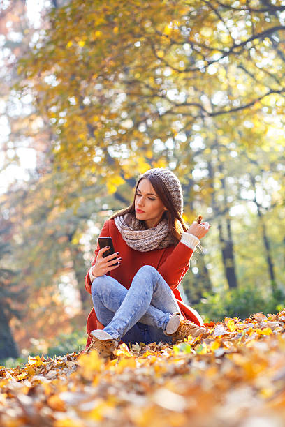 istock Young woman with smart phone relaxing in park 496102604