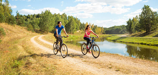 Young Happy Couple Riding Bicycles by the River stock photo