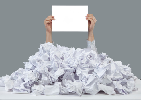 Hands reaches out from big heap of crumpled papers