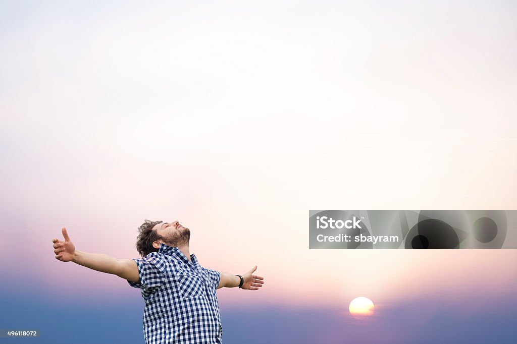 Young man with arms raised A peaceful young man opened his arms with sunrise Men Stock Photo