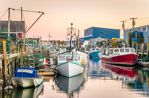 Harbour with colourful fishing boats at sunset. Lots of lobster traps are piled on the wooden piers. Great reflection in the calm water. Portland, Maine.