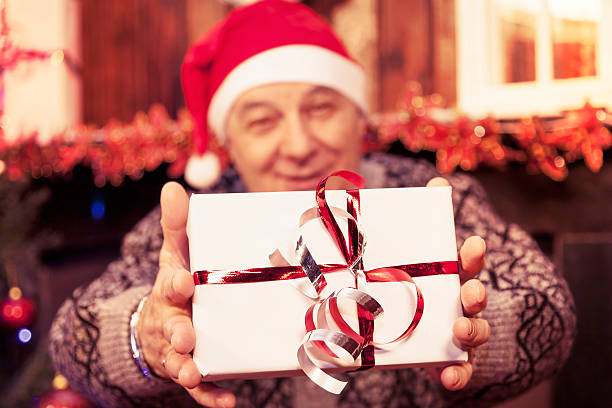 istock mature man holding a red christmas gift box 496119386