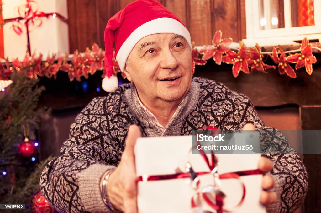 mature man holding a red christmas gift box mature man holding a red christmas gift box in his hands 2015 Stock Photo