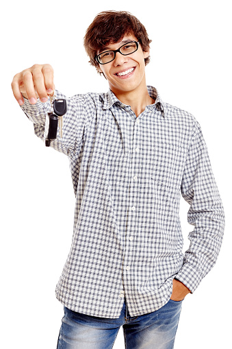 Young hispanic man wearing checkered shirt, blue jeans and black glasses holding out car keys and smiling isolated on white background - new drivers concept