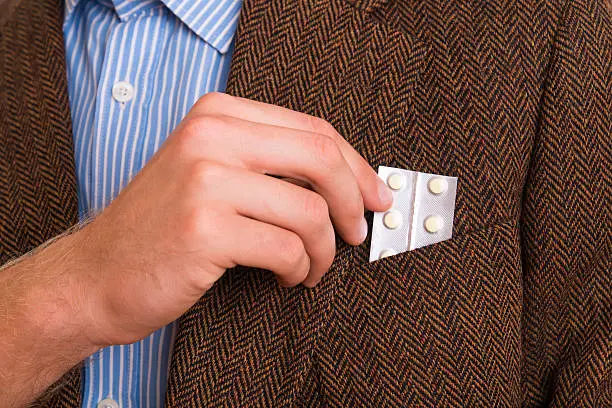 Photo of Man puts pills into his pocket in the jacket