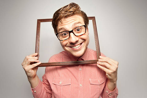 istock A geeky looking man holding a picture frame around his neck 496157251