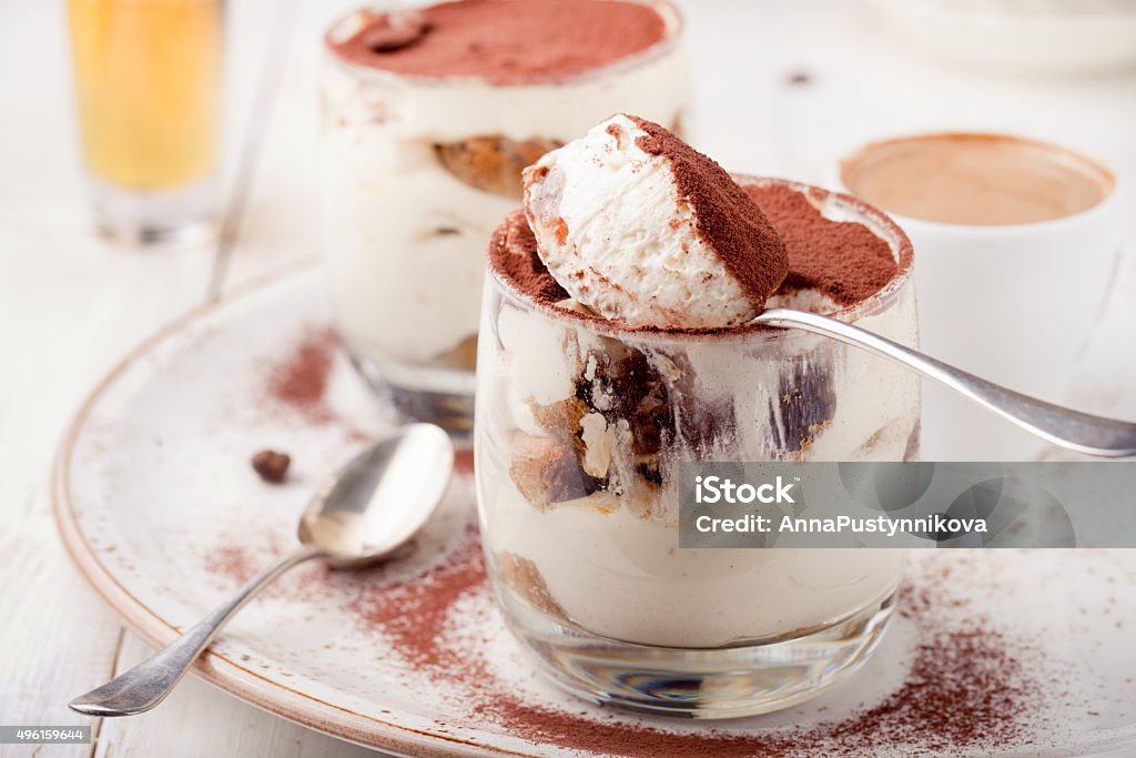 Tiramisu dessert in a glass. Traditional Italian. Tiramisu dessert in a glass on a white wooden background, traditional Italian. Tiramisu Stock Photo