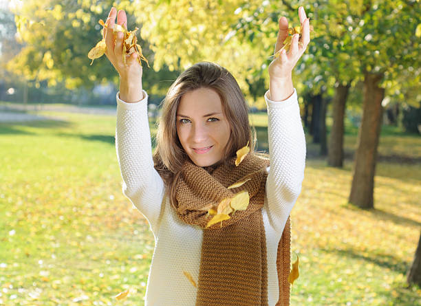 istock Happy young woman throwing autumn leaves 496160518