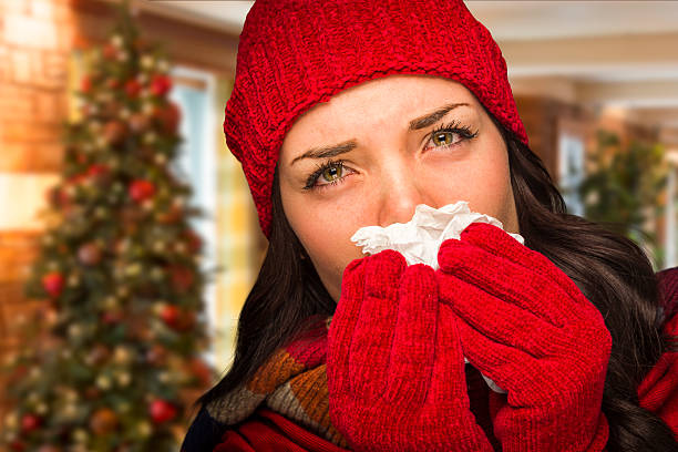 sick mujer soplando su alcance en el ambiente de navidad con tejido - sniffles fotografías e imágenes de stock