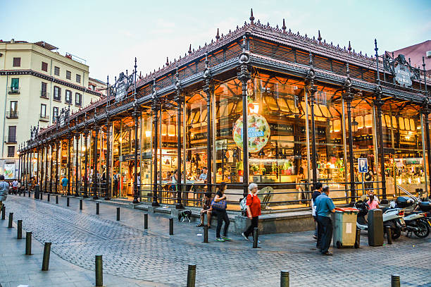 San Migeul Market in Madrid, Spain Madrid, Spain - August 6, 2015: Tourists visiting the famous San Miguel Market, Madrid. The market wants to be part of the agenda of Madrid events doing different activities related to leisure and culture, helping to revitalize the old capital. food court photos stock pictures, royalty-free photos & images