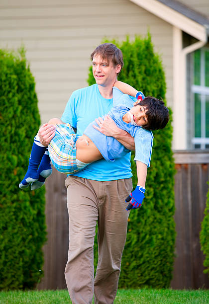 istock Father carrying disabled son outdoors 496198333