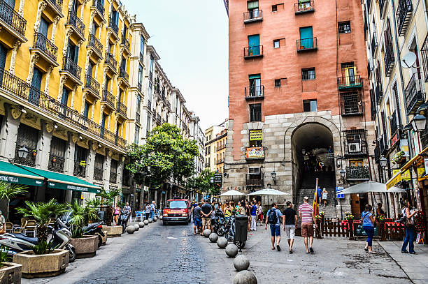 Madrid, Spain - August 8, 2015: Typical plaza and street in Madrid featuring store fronts, restaurants, and tourists. Taken during the day in summer.