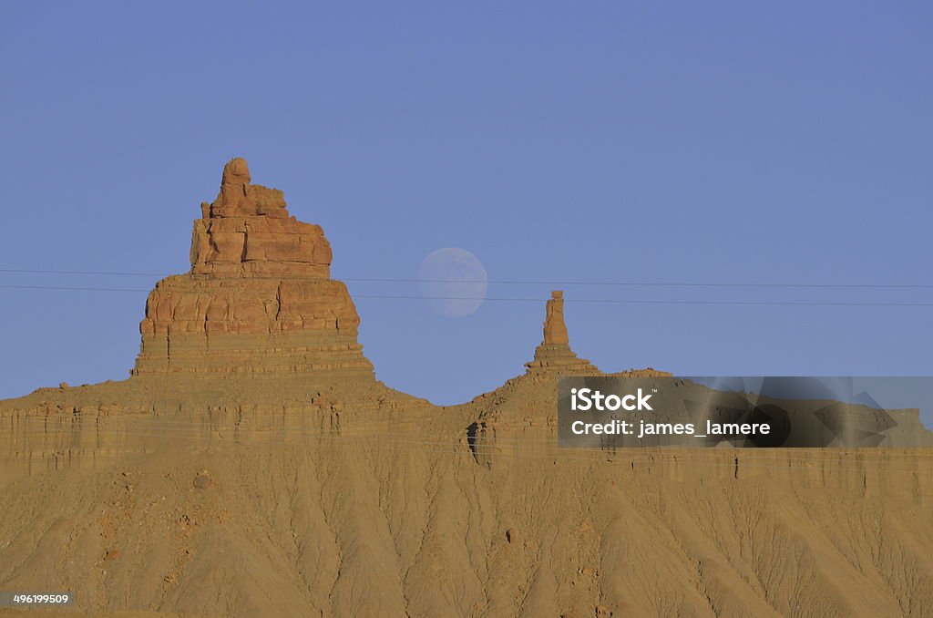 Sunset Full Moon Rising over Red Rock Ridge Sunset full-Moon rising over a red rock ridge on the Southern Ute Indian Reservation on Mesa Verde in southwest Colorado. Three electrical power lines span across the foreground. Blue Stock Photo