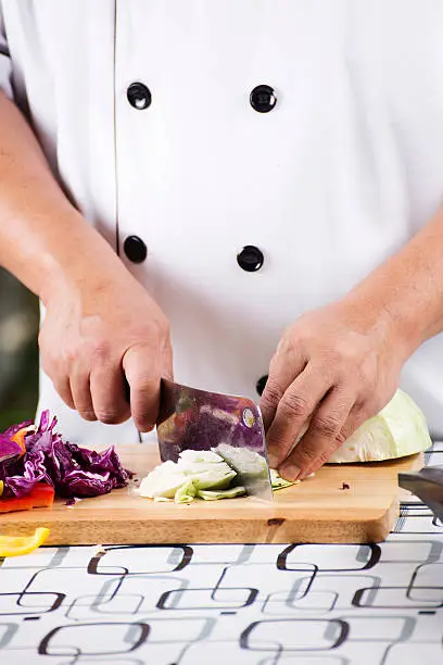 Chef cutting green cabbage on wooden broad
