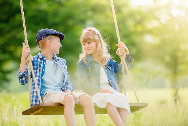istock Young boy and girl sitting on a swing 496199938