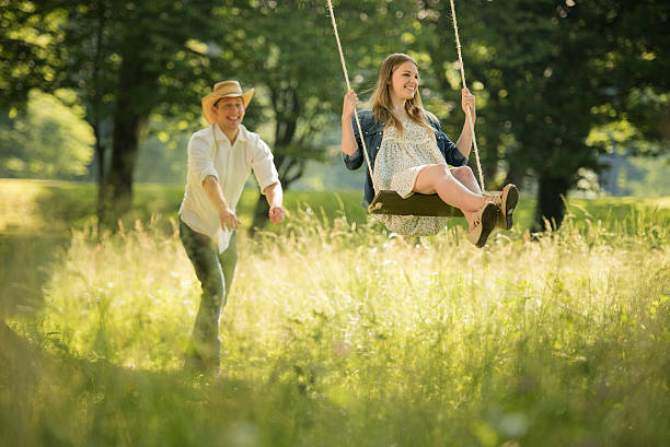 istock Boyfriend pushing his girlfriend on a park swing 496200138