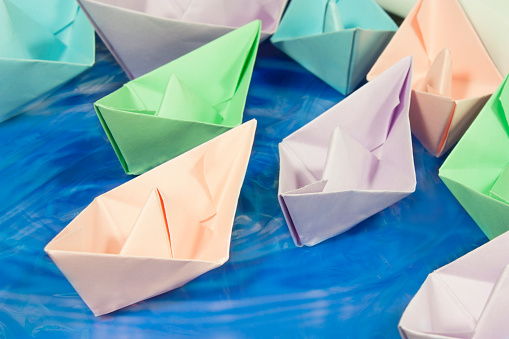 colored paper boats sailing in troubled waters