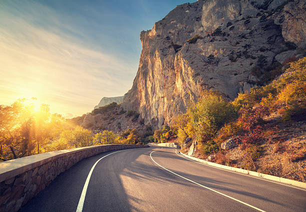 strada asfaltata in autunno foresta all'alba. monti di crimea - autumn road landscape mountain foto e immagini stock