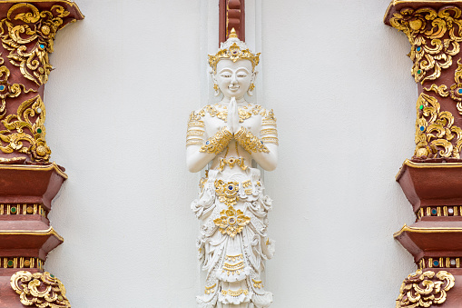 Stucco statue of guardian angel in salute posture at Wat Phra singha, Chiangrai, Thailand.