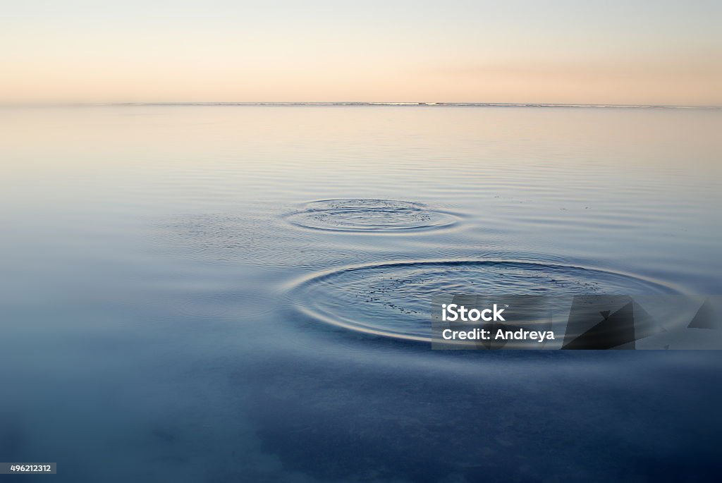 Ripples on the tide Round ripples from skimming a pebble on the surface of the ocean, pink light, soft focus Skimming Stones Stock Photo