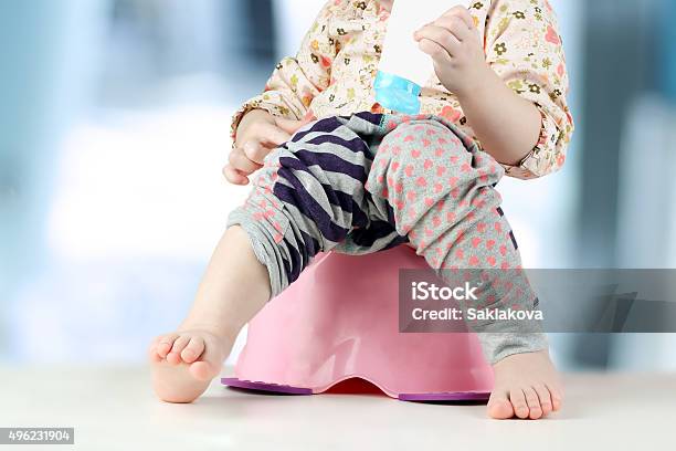 Childrens Legs Hanging Down From A Chamberpot On A Blue Stock Photo - Download Image Now