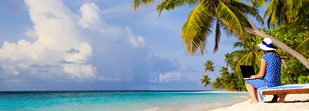 istock young woman with laptop on tropical beach 496234624